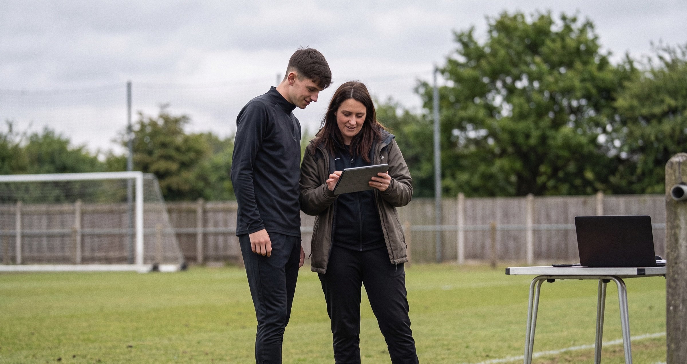 A young athlete and a parent looking at results on a tablet at the pitch edge
