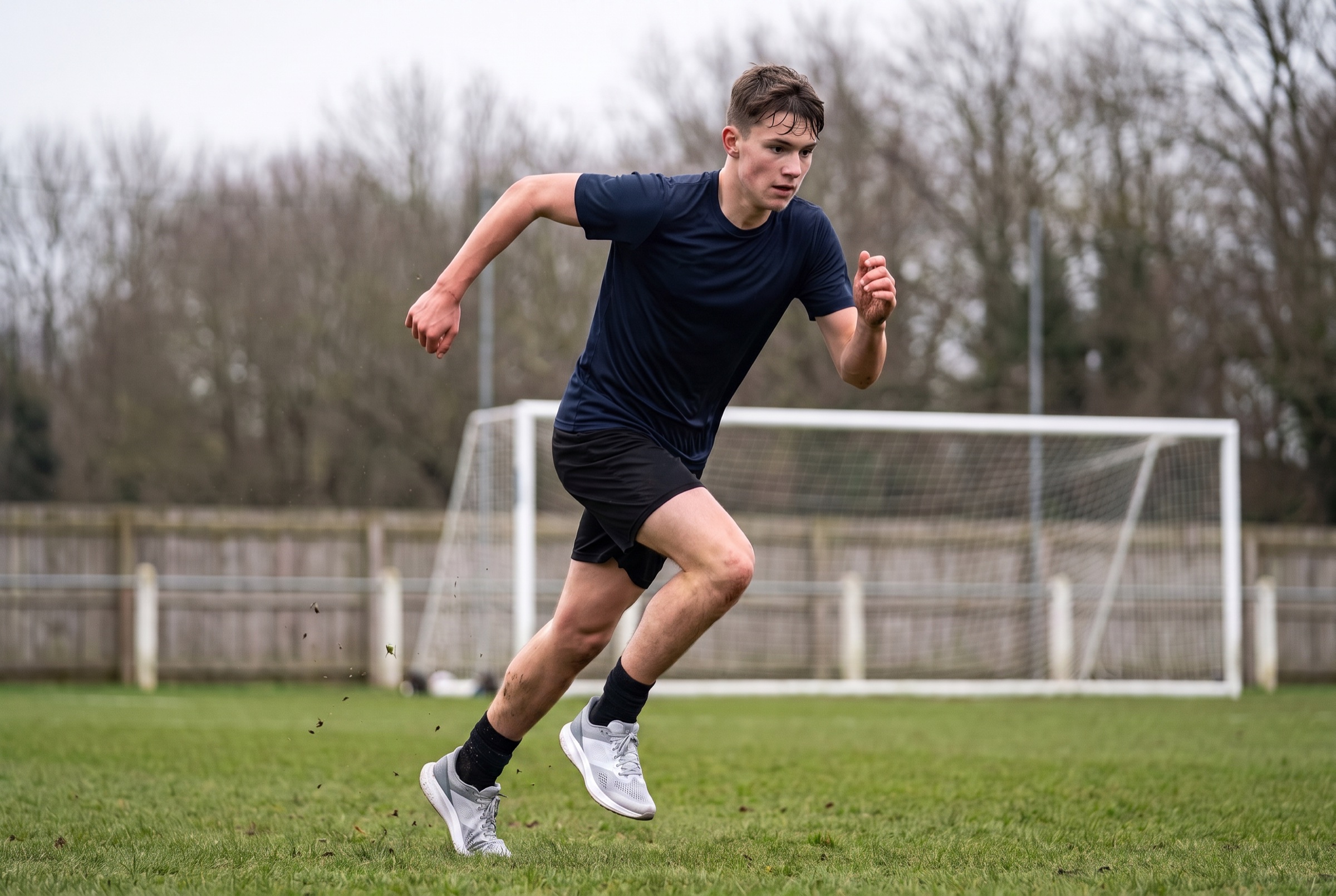 A footballer at full sprint across a floodlit pitch at night