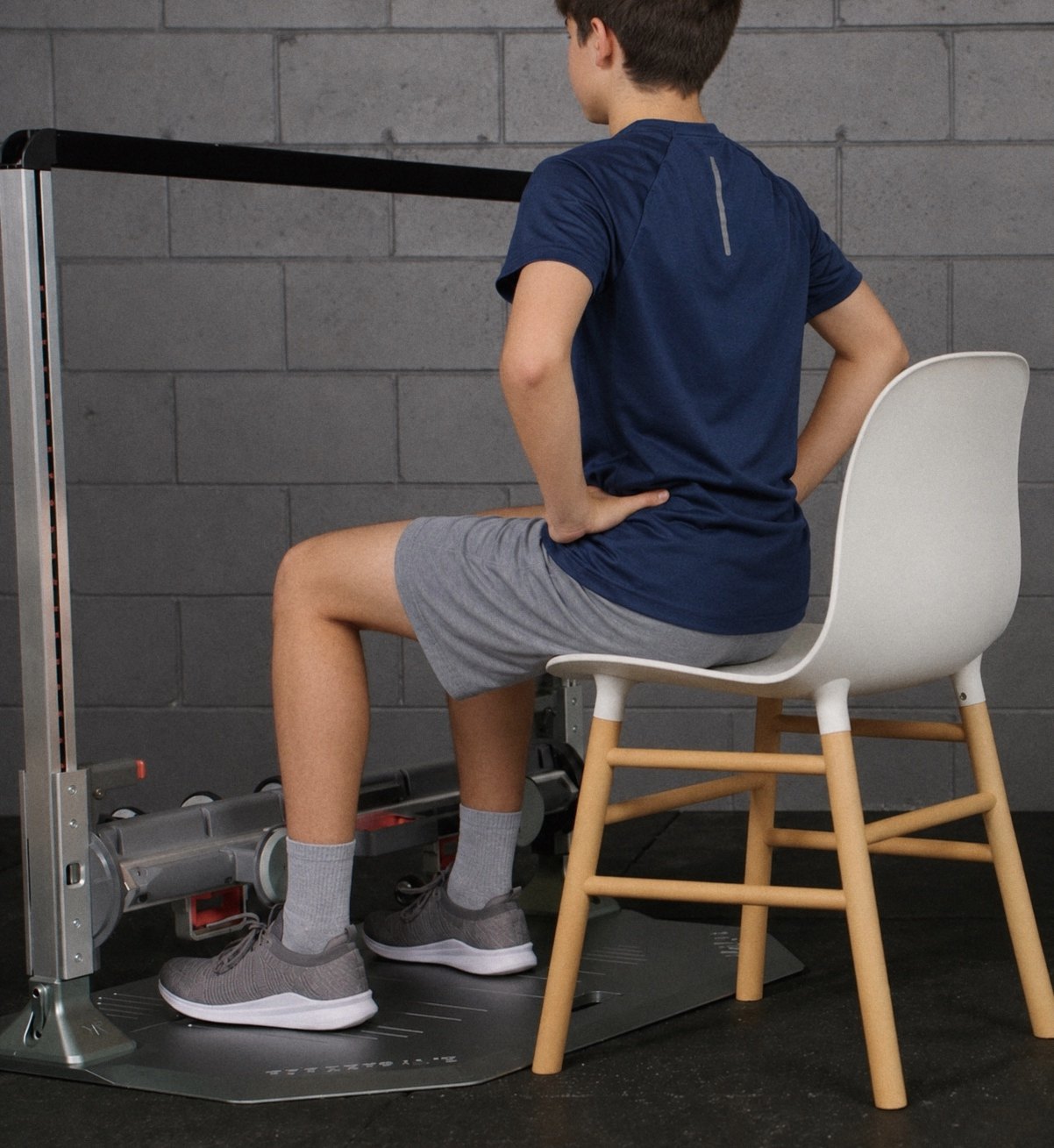 A youth athlete seated in a strength testing frame during a knee strength test
